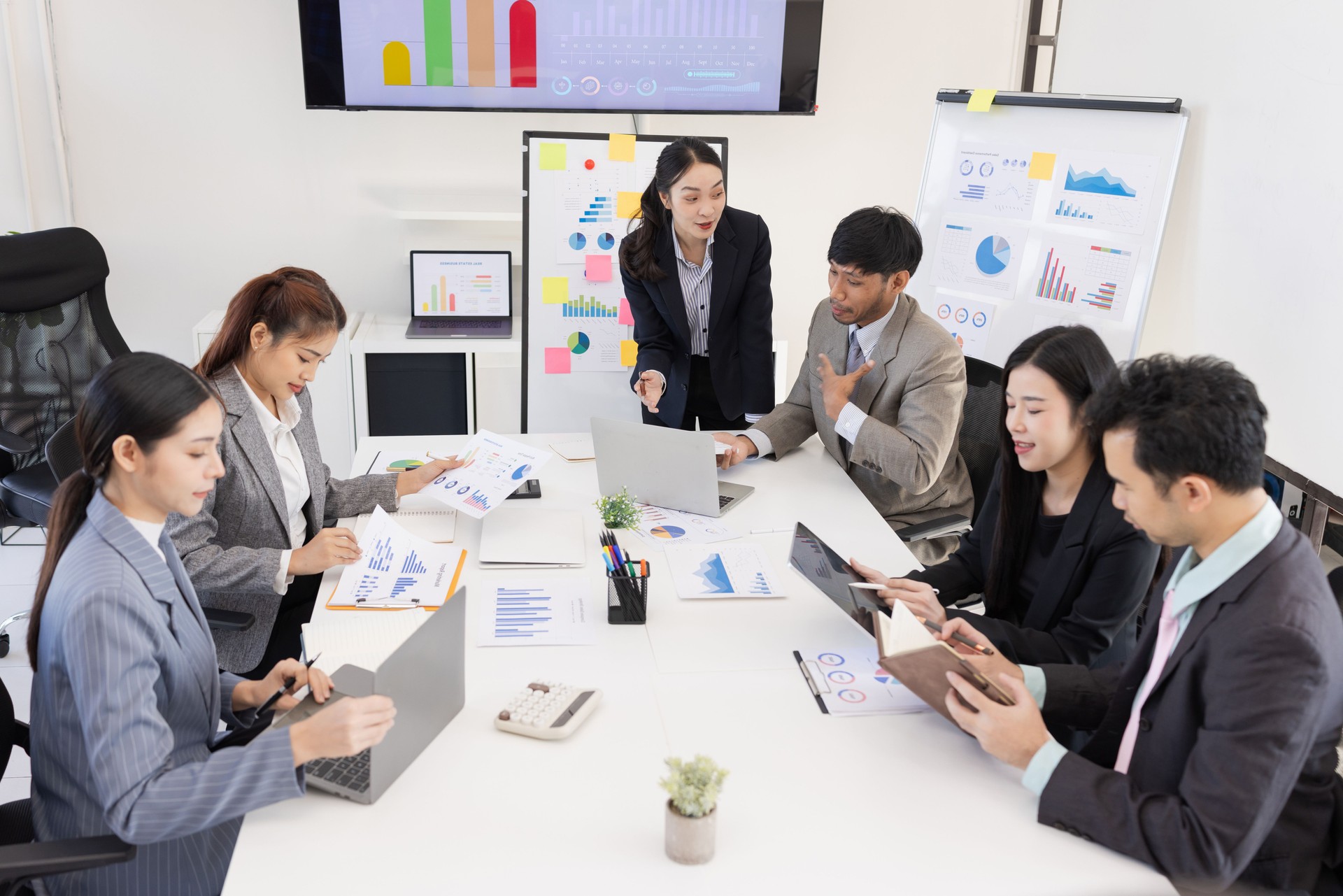 Group of business people working together with dashboard analysis and data management in meeting room.